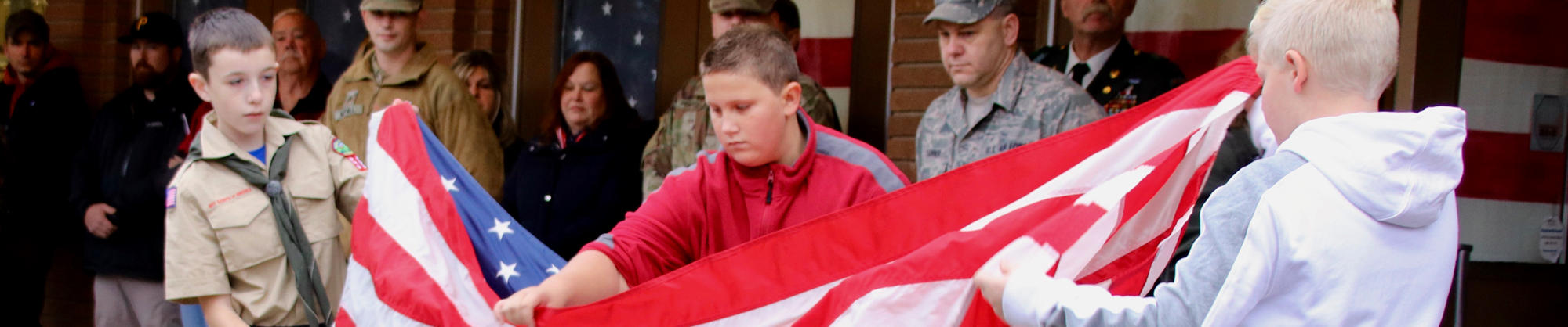 three boys folding the United States of America Flag