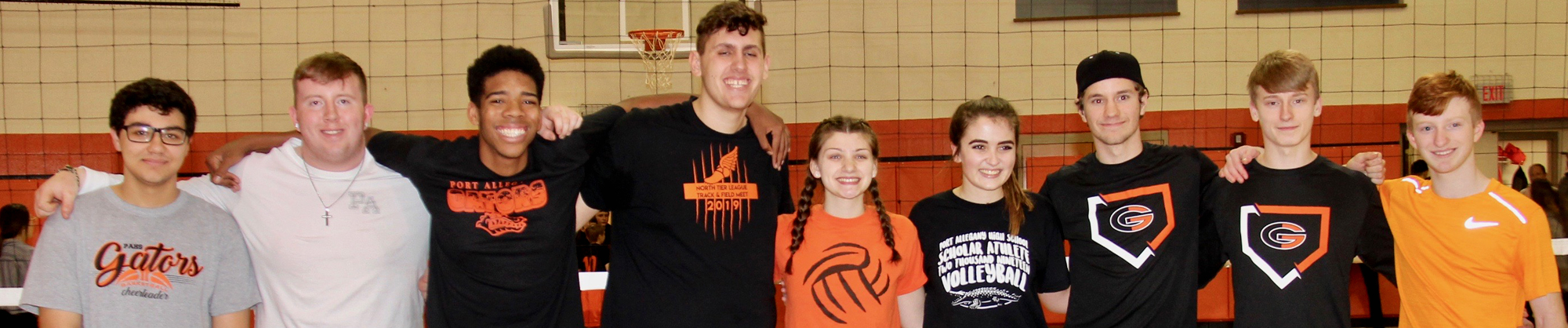 nine students standing arm in arm on the volleyball court