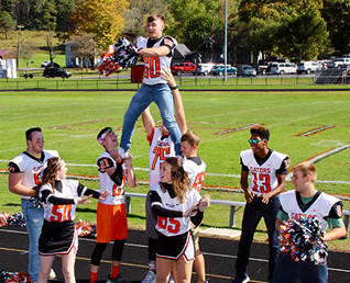 boys in football jerseys doing cheers with the cheerleaders 