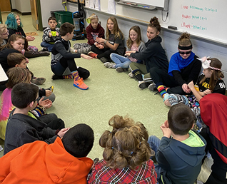 young students all sitting on the ground in a circle