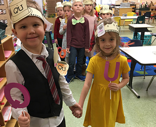 a little boy holding the letter Q and a little girl holding the letter U