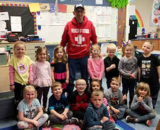elementary students in the classroom with a staff member