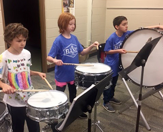 three students playing the drums